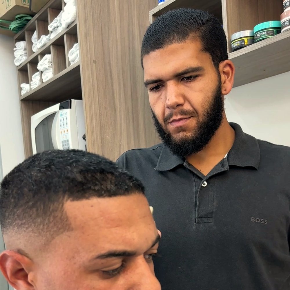 Dudu conferindo o degradê de um cliente na Eduardo Barbearia